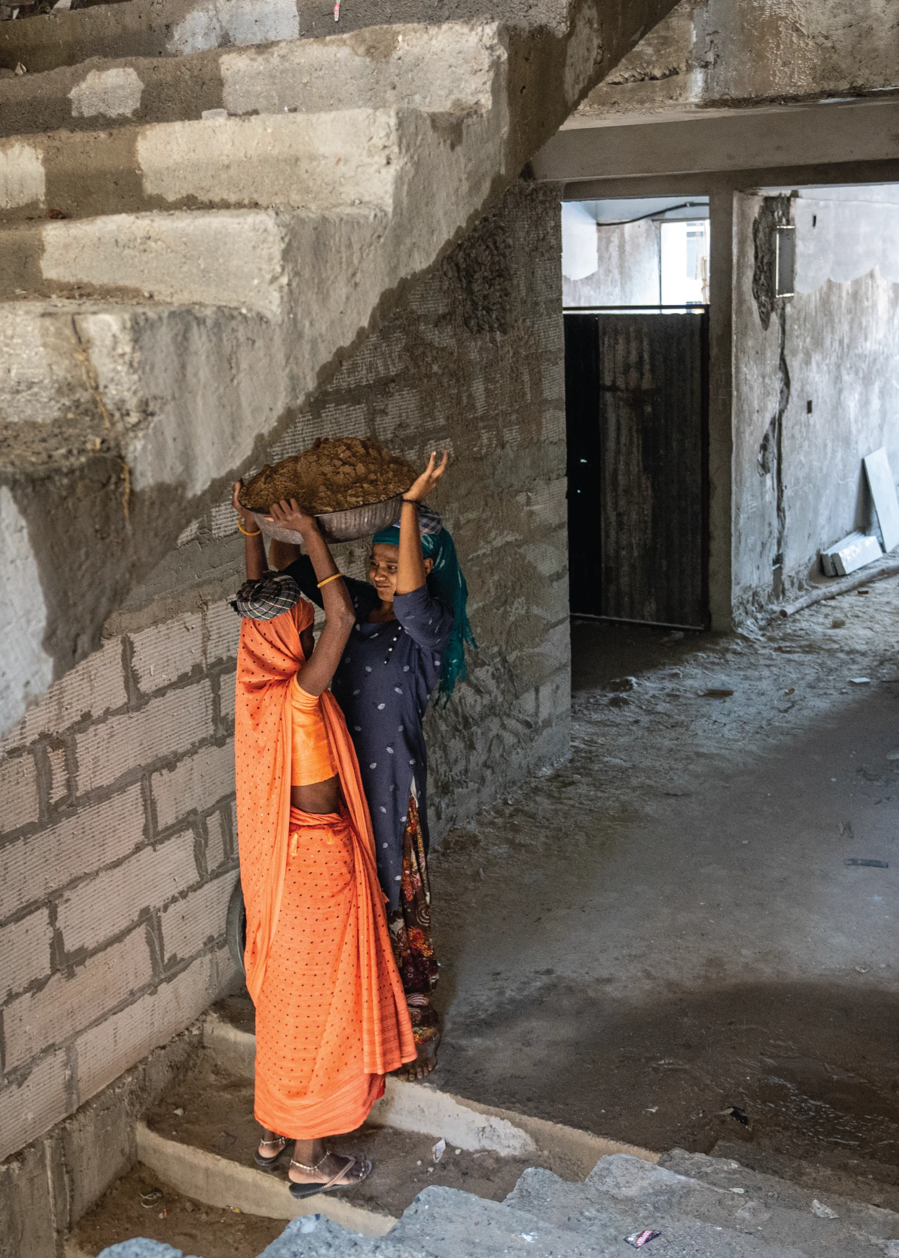 Two girls in India carrying building materials